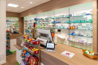 Der Kassenbereich der Delphin Apotheke mit Glasschränken Angeboten und Verkaufsarktikel