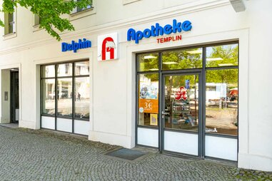 Frühlingshaftes Bild Eingangsbereich Delphin Apotheke Templin Glasfassade und Logo
